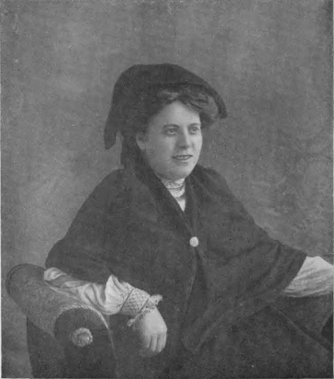 The upper body of the
author is shown formally posed seated, with a soft hat-like covering for much of her
hair and a shawl with a clasp over a long-sleeved blouse.